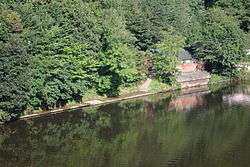 A picture of Durham School Boat Club's boat house in summer, taken from Prebends Bridge