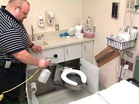 Non-flammable alcohol vapor in carbon dioxide systems being used as the final step in sanitizing a swing out toilet in a hospital ER exam room.