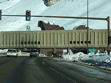 partial view of a traffic signal leading to a hole in a snow covered building.