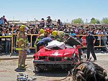Emergency responders rescuing victims at a simulated car crash scene.