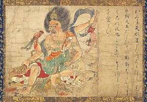 A deity embellished with ornaments and four arms grabbing three much smaller persons in three of his hands and the lower body part of another in his fourth hand. To the right of the scene there is Japanese calligraphic text.