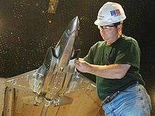 Engineer handling a metallic scale model of jet fighter in wind-tunnel