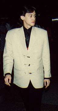 An Indonesian man, standing stiffly, wearing a white jacket