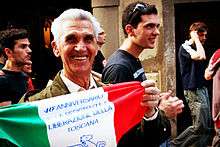 Smiling older man in a parade, holding a decorated Italian flag
