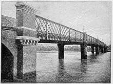 Narrow lattice truss bridge crossing a wide river