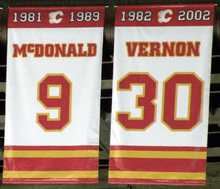 Two rectangular banners, both white with red and yellow trim at the top and bottom.  The left one says "1981 – 1989 McDONALD 9" and the right "1982 – 2002 VERNON 30"