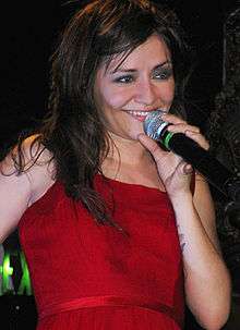 A woman wearing a red dress is holding a microphone up to her mouth.