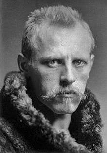 Head and shoulders portrait of Fridtjof Nansen, facing half-right. He has close-cropped hair, a wide, fair moustache and is wearing a heavy fur coat.