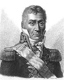 Blank and white print of a stern-looking man with heavy eyebrows. He wears a dark military coat with a high collar, epaulettes, gold braid and a sash over his shoulder.