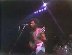 Garry Shider in 1978 touring with Parliament-Funkadelic. He is in his trademark diaper look. The is 23 years old and playing guitar, standing in front of a microphone and preparing to sing.