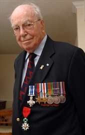 Older gentleman in jacket and tie with a row of medals on his chest