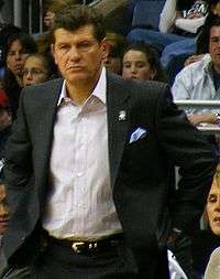 Half-length shot of a man. He is wearing an open sports coat with a white shirt underneath.