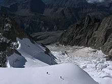 climbers crossing snow above a steep glacier