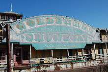 A faded blue, pink, and gold sign sits on the side of a rusting showboat and displays the words, "GOLDENROD / NATIONAL LANDMARK / SHOWBOAT / St. Charles, Missouri".