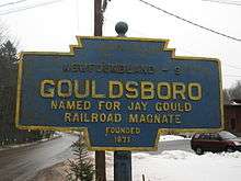 A blue sign with gold border reading "NEWFOUNDLAND - 9/GOULDSBORO/NAMED FOR JAY GOULD/RAILROAD MAGNATE/FOUNDED/1871" in gold lettering, with a snowy scene in the background.