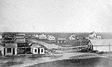 Black-and-white photo: ca. 20 one-story buildings on treeless prairie