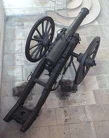 Top-view photo of a French cannon on a wheeled carriage. The top of the barrel includes a pair of handles