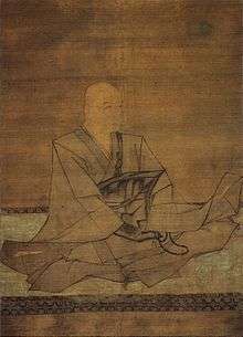 Seated monk holding a rosary in three-quarter view.