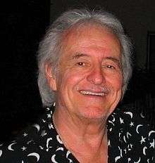 A man with grey hair, wearing black and white shirt.