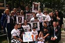 Henry Nicholas (center), his mother, Marcella Leach (standing, far left),Crime Survivors founder Patricia Wenskunas (standing, fifth from left), victims' rights advocate Collene Campbell (standing, second from right) and former Orange County Deputy District Attorney Todd Spitzer (seated, far right) join with victims and families in downtown Los Angeles to commemorate the annual National Day of Remembrance for Murder Victims.