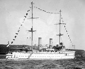 Black-and-white photograph of white ship with tall masts.