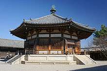 Large octagonal wooden building with white walls.