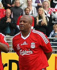 Middle-aged black man wearing a red football shirt with white emblems and Carlsberg logo