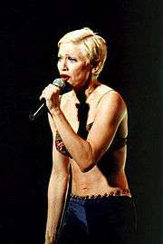 A singer with short blonde hair is performing