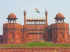 The national flag of India hoisted on a wall adorned with domes and minarets.