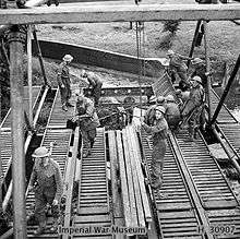 A photograph showing a number of Royal Engineers sappers constructing an Inglis Bridge across a river
