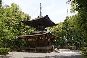 A wooden two-storied pagoda with a square base, round top and a pyramid shaped roof.