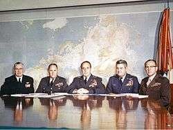 A group of five men in military uniform seated at a table
