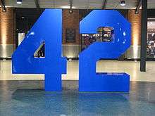 An eight-foot blue sculpture of a stylized uniform number, 42, set atop a polished interior walkway