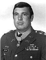A black and white image showing the head and upper torso of Taylor wearing his military dress uniform with ribbons. His Medal of Honor can be seen around his neck.