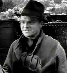 Head and shoulders shot of Cagney, wearing black fedora and smiling slightly, scenery in the background