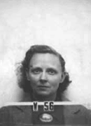 Mug shot of woman with glasses in suit The number V-56 appears in front of him.