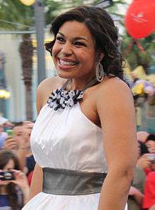 A white woman wearing a white dress, smiling.