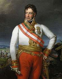 Painting of an overweight man with his left hand on a sword hilt and his righ hand holding a glove. He wears a military uniform consisting of a white coat and red breeches with a red and white sash across his shoulder and a gold sash around his waist.