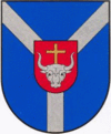 A coat of arms depicting a grey bull's head with a golden cross protruding from the top all on a red crest on a blue background