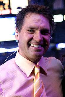 Kelly Hrudey smiling in a pink button-up shirt with a tie on