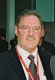 Kevin Beattie wearing a dark jacket, a white shirt, and black-and-white polka dot tie