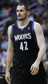 A basketball player, wearing a black jersey inscribed with the word "WOLVES" and the number 42 on the front.
