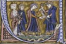 A bearded man wearing a crown gives a falcon to a younger man who is accompanied by a woman and a man
