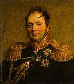 Painting shows a chubby, balding man with round face. He wears a very dark military uniform with gold epaulettes and a red and gold collar.