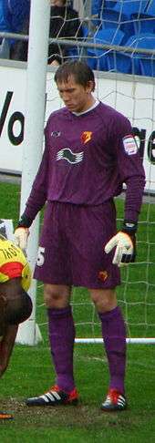 White man in sports kit standing near a goal