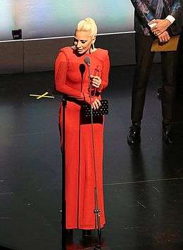 Lady Gaga wearing a red outfit and holding an award
