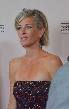 A woman with short blond hair, wearing a sparkly brown dress.