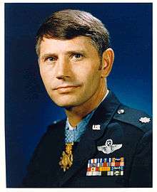 A color image showing the head and upper torso of Thorsness wearing his military dress uniform with ribbons. His Medal of Honor can be seen around his neck.