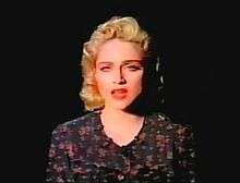 The portrait of a young blond woman. She sports flowing blond hair and a black dress. She has a sad expression on her face which is illuminated by a single source of light.
