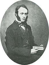 A young man with dark hair and huge sideburns